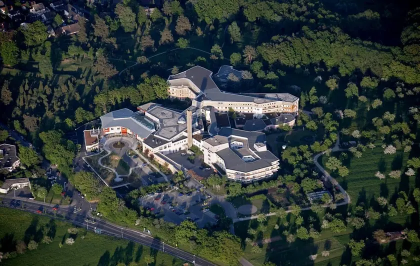 Vue aérienne d'un bâtiment moderne entouré de verdure et de jardins.