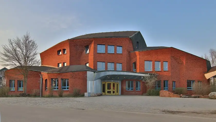 Bâtiment moderne en briques rouges avec un toit en pente et de grandes fenêtres.