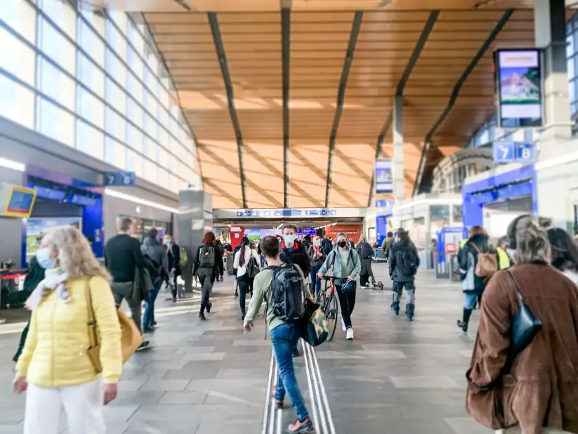 Une foule de passagers se déplaçant dans un hall d'aéroport moderne avec un plafond en bois.