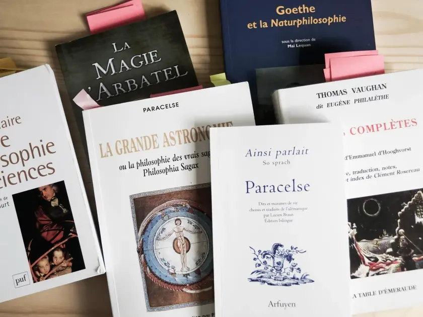 Une collection de livres sur la philosophie, l'astronomie et Paracelse, avec des marque-pages colorés.