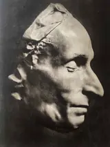 Un masque en plâtre représentant un visage humain de profil, avec des traits marqués et une texture détaillée.