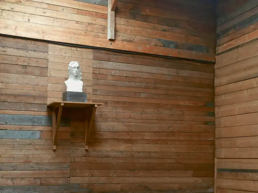 Un buste en marbre posé sur une étagère en bois dans une pièce aux murs en bois.