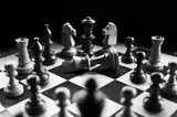 Échiquier en noir et blanc avec des pièces de jeu, dont un roi renversé au centre.