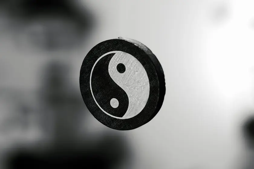 Symbole du yin et du yang en noir et blanc, flottant sur un fond flou.
